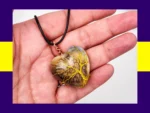 Heart-shaped resin pendant with yellow tree-of-life wire wrapping displayed in hand – earthy, nature inspired handmade necklace