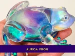 Close-up of the handmade aurora resin frog held in hand to show its colour-shifting detail.