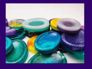 Close-up of several handmade resin calming stones stacked in a row, showing the variety available in the Chaos Solo lucky dip.