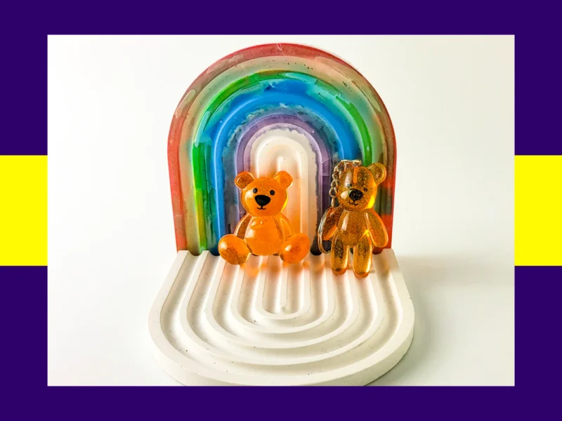 Orange resin Worry Bear handheld and keyring pair displayed on white rainbow arch tray – glitter resin calming bears