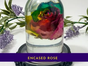 Close-up of the encased rose resin dome with a purple banner reading “ENCASED ROSE” at the bottom.