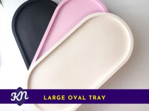 Three large oval eco-resin trays stacked (black, pink and white) on a white background, used as the primary product image for the Large Oval Tray.