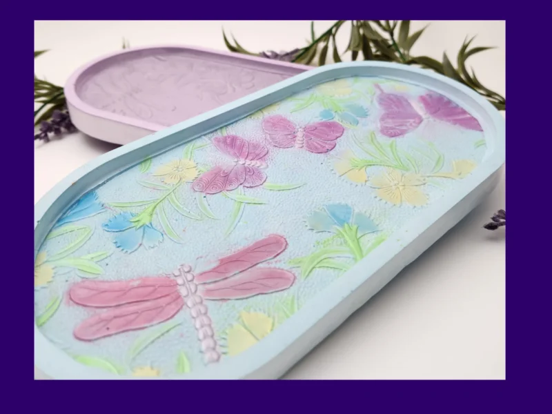 “Front view of pastel resin trinket tray featuring raised dragonflies, butterflies and floral details.”