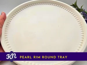 Primary-Listing-Image.webp: White Pearl Rim Round Tray with beaded rim, held in hand with greenery in the background; product title banner on the image.