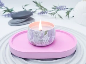 Small oval eco resin tray in soft pink styled with a lit candle on top, modern catchall tray for bedside or coffee table use.