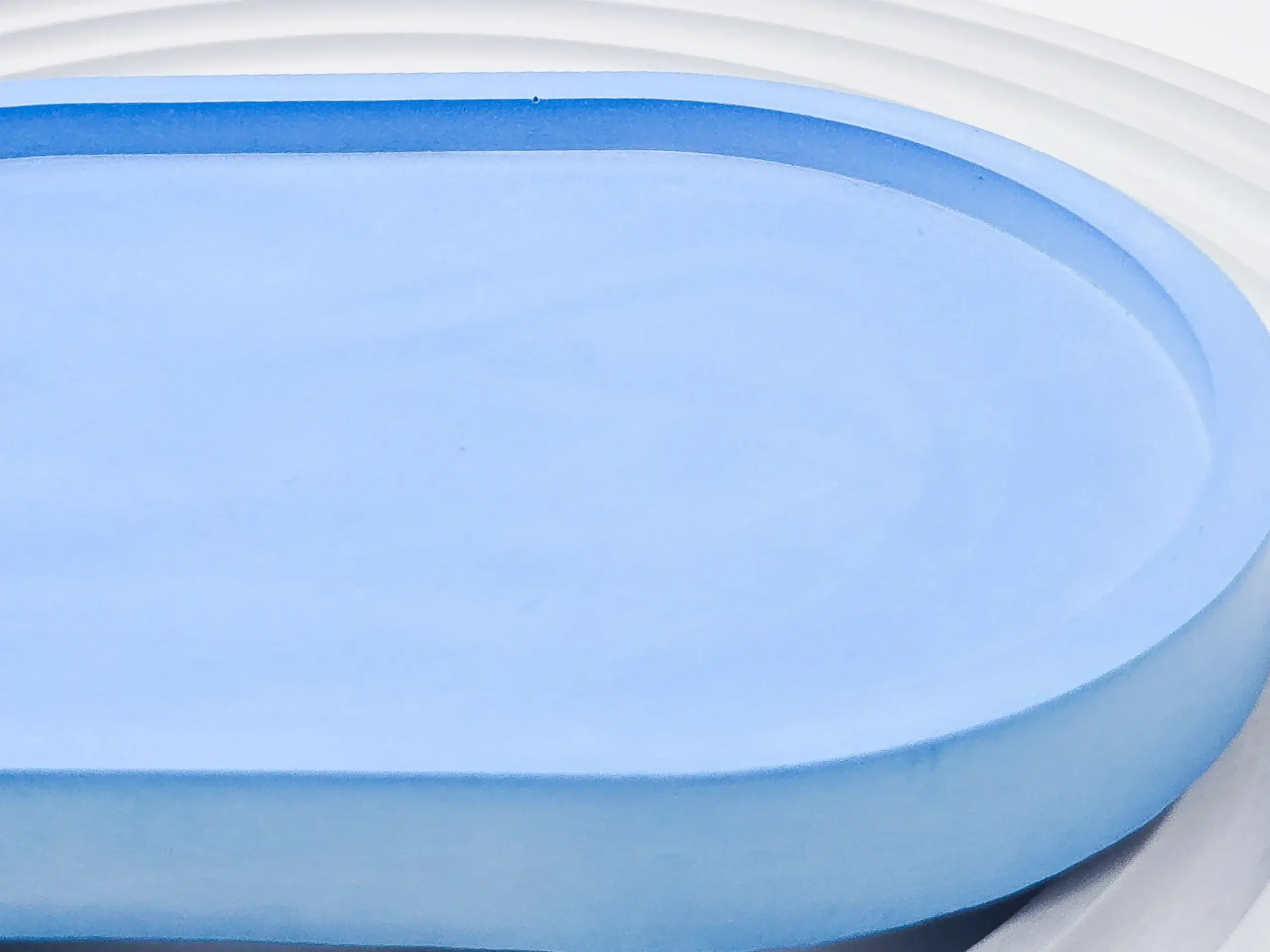 Close-up side profile of light blue eco resin tray showing thickness and smooth rounded edge.