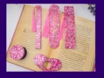 Pink glitter bookmark set laid out on an open book (all five styles visible).